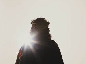 Silhouette of Jesus facing the sun with a crown of thorns upon his head.
